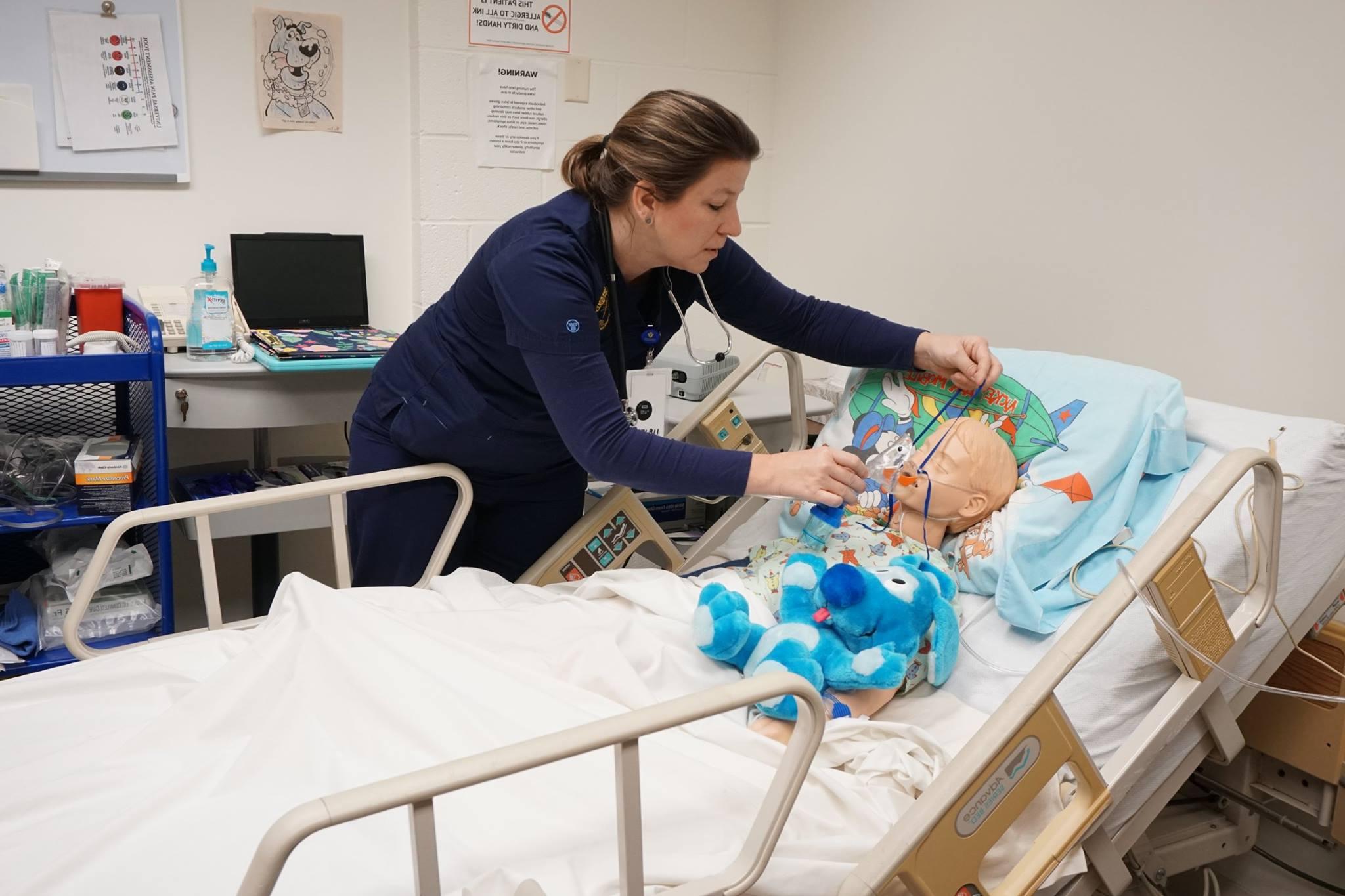 Nursing student putting a mask on a practice dummy